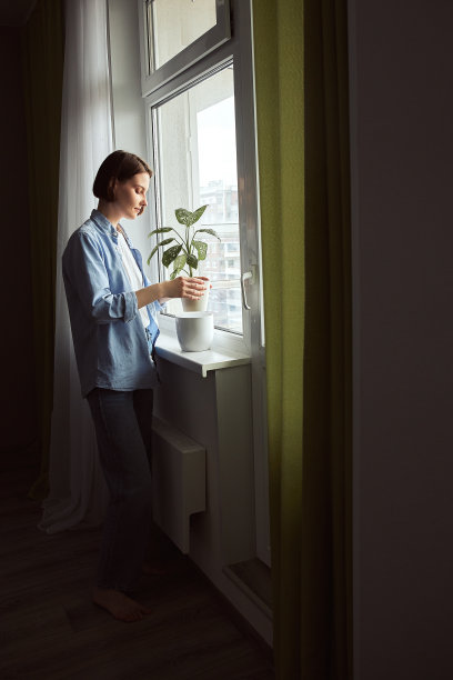 年轻的女人照顾绿色的盆栽。图片下载