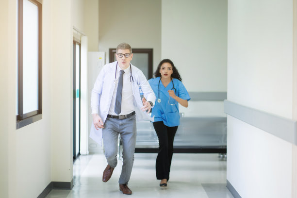 男医生和女护士在医院的走廊里奔跑。医药保健理念。图片下载