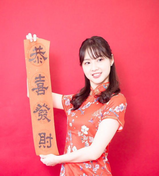 年轻的亚洲妇女穿着传统旗袍旗袍举行中国节日对联庆祝新年与新年的意思在红色的背景。图片下载
