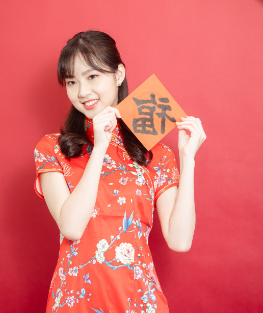 年轻的亚洲妇女穿着传统的旗袍旗袍举行中国节日对联庆祝新年与汉字“福”(福的意思是祝福，幸福)在红色的背景。图片下载