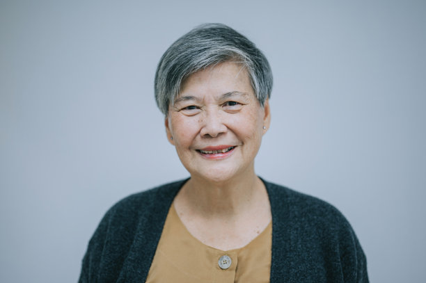 肖像亚洲中国年老妇女看着相机与白色背景微笑图片下载