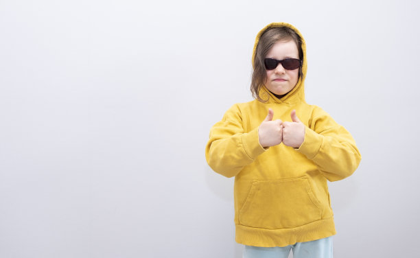 表情和手势。一个戴着墨镜的女孩微笑着，用手势表示她喜欢什么，喜欢什么。一个六岁白人女孩的肖像，复印的空间。图片下载