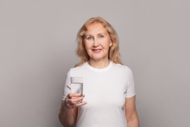 快乐的高级妇女饮水。拿着一杯水的成熟女士图片下载