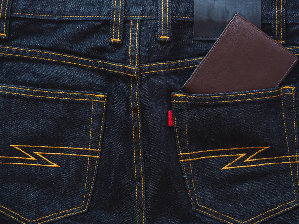棕色皮革钱包上的牛仔裤背景。图片下载