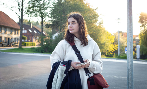 一个年轻女人清晨在公共汽车站的肖像。图片下载