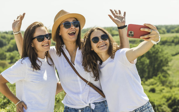 三个快乐的成年女性戴着太阳镜在自然中自拍旅行。素材图片