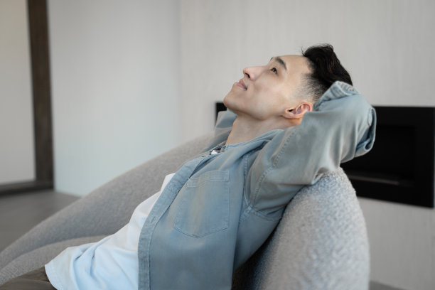 亚洲人靠在扶手椅上听动感的音乐图片下载