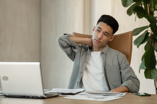 年轻的亚洲人在办公室的桌子上揉脖子工作图片下载