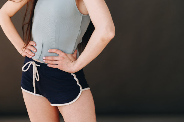 手放在腰上的身体部位的特写照片，灰色t恤和短运动短裤图片下载