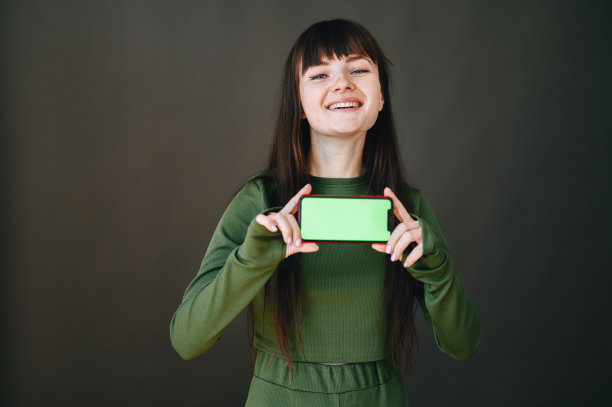 女孩大声笑着，双手拿着手机，绿色屏幕朝前图片下载