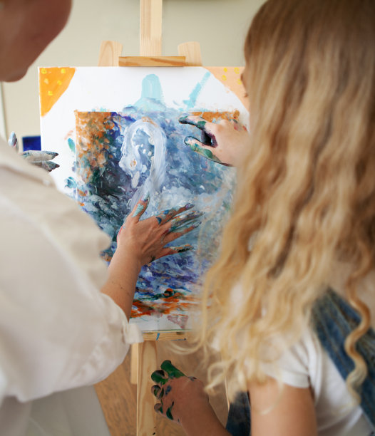 女老师和金发女孩用手在画布上画丙烯颜料。艺术学校的治疗图片下载
