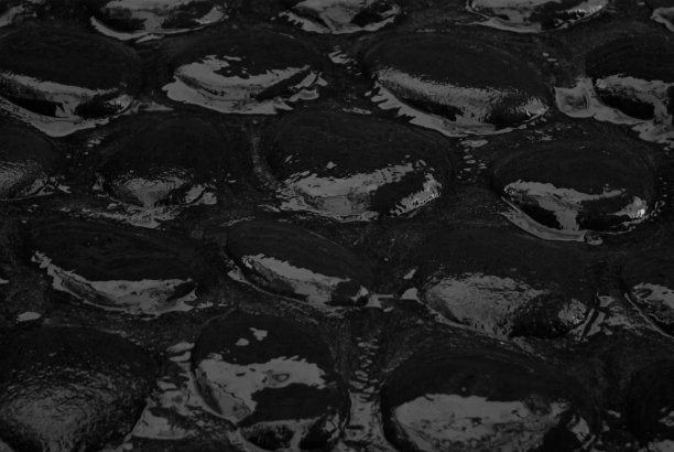 潮湿的黑色鹅卵石路面光滑的火山鹅卵石与反射，纹理，顶视图，特写，背景。图片下载