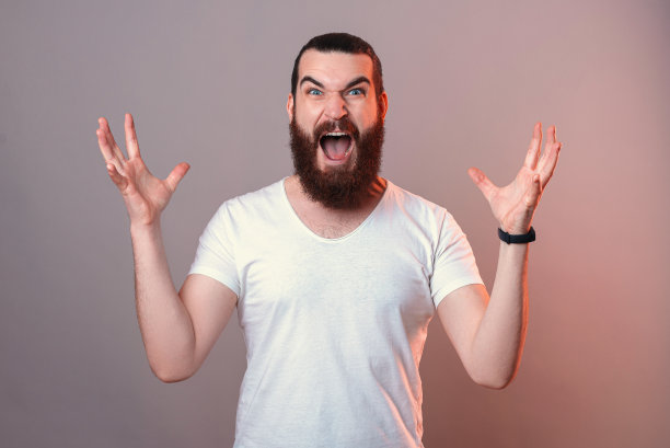 在画室里，一个满脸胡须的年轻男子正在用双手做手势。图片下载