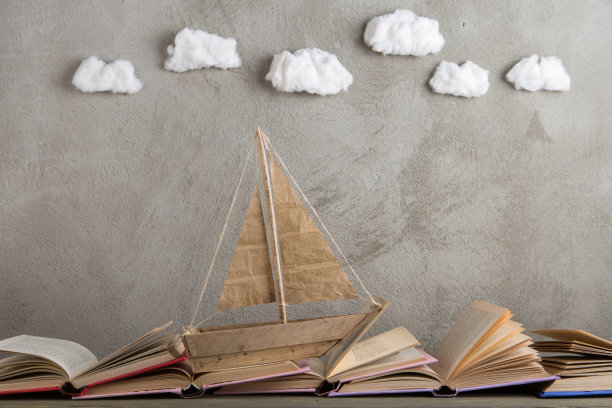 教育是一种旅程的概念，玩具船和书籍就像海浪在木桌上，灵感来源于写一个童话图片下载
