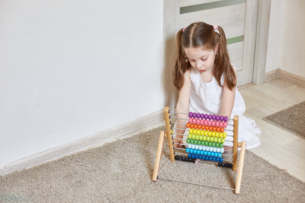 一个穿着白裙子、扎着马尾辫的漂亮小女孩正在学习依靠孩子们的帐户。孩子的教育。图片下载