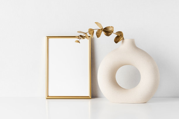 金色框架模型和圆形陶瓷花瓶与金色桉树枝在白色的桌子上图片下载