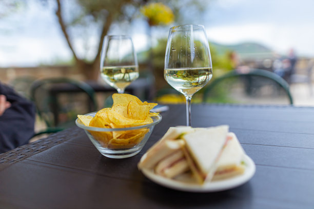 两个人的餐桌，一盘三明治和薯片，两杯酒图片下载