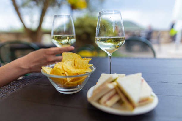餐厅两个人的桌子，盘子里有三明治和薯片，一个陌生的人拿着酒杯图片下载