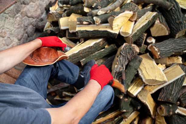 戴着红色手套的男人坐在一堆柴火上图片下载