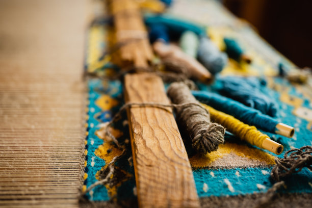 在踏板织布机和地毯正在被制造的过程中，不同颜色的羊毛线线轴的极端特写照片图片下载