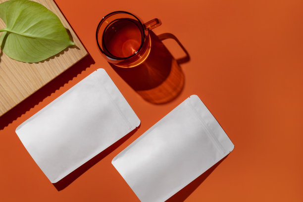 白色纸板包装的茶和杯子与茶在橙色的背景。品牌和包装模型。图片下载