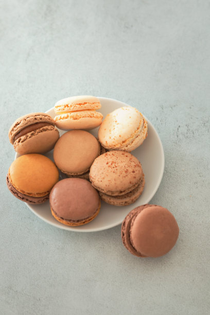 带马卡龙蛋糕的盘子在灰色背景上拷贝空间。糖果——坚果巧克力马卡龙。带有复制空间的垂直照片。图片下载