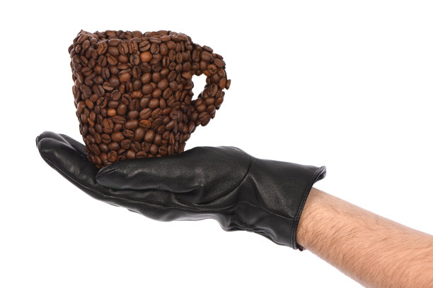 在白色背景上戴黑色皮革手套的人，特写。手里拿着一杯咖啡豆。图片下载