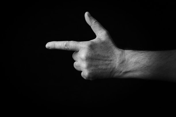 反手指数指向左边的表情符号孤立在黑色背景图片下载
