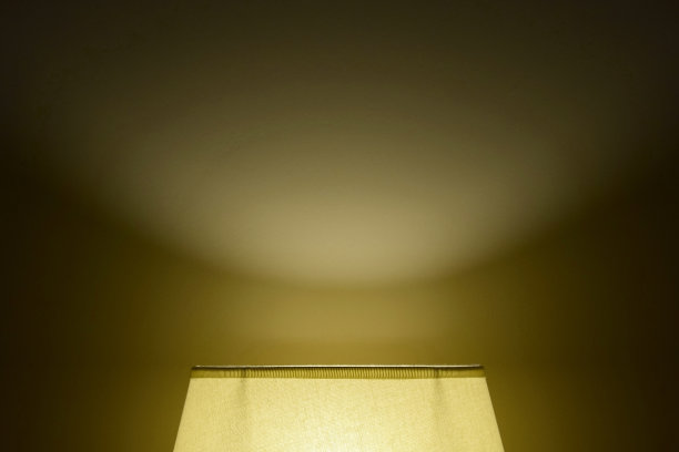 在黑暗的房间里，从墙上的灯罩上射出的柔和的光线。背光。图片下载