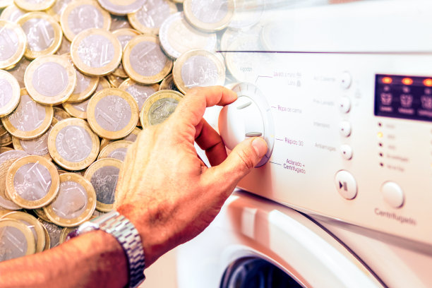 照片蒙太奇显示，一名男子的手转动洗衣机轮子，后面是欧元硬币。能源成本的概念。图片下载