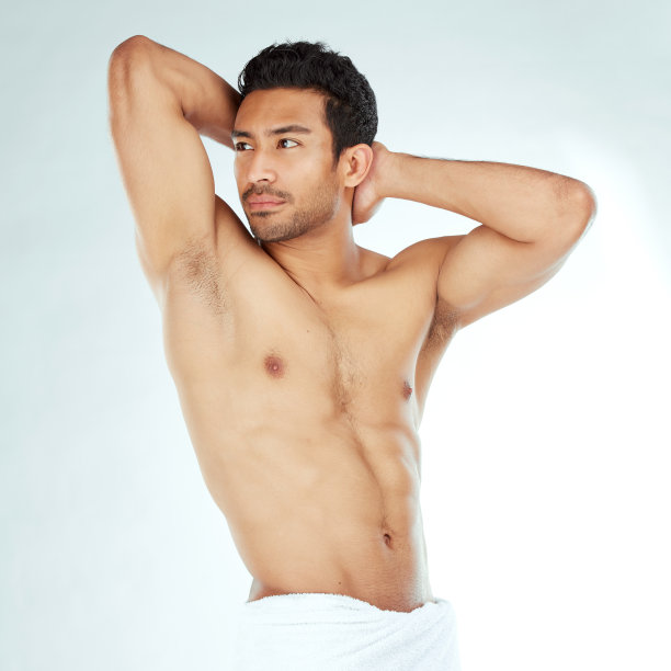 一个英俊的年轻男子在一个工作室背景下穿着毛巾摆姿势图片下载