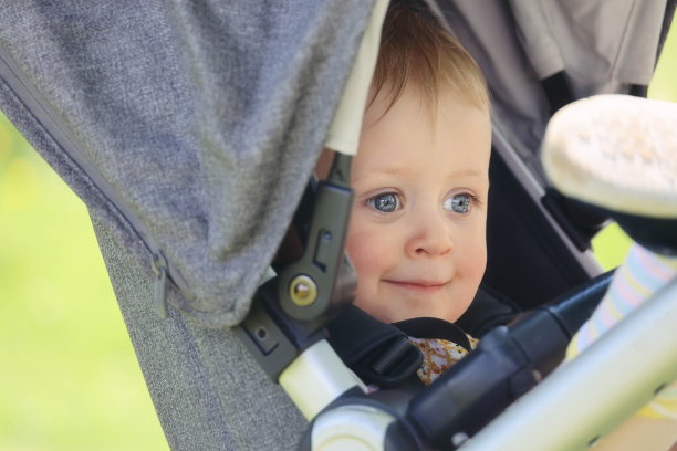 快乐的宝宝坐在婴儿车里享受春日阳光图片下载