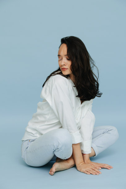 为一张照片摆姿势的白癜风黑发女子盘腿坐着，靠在她的胳膊上图片下载