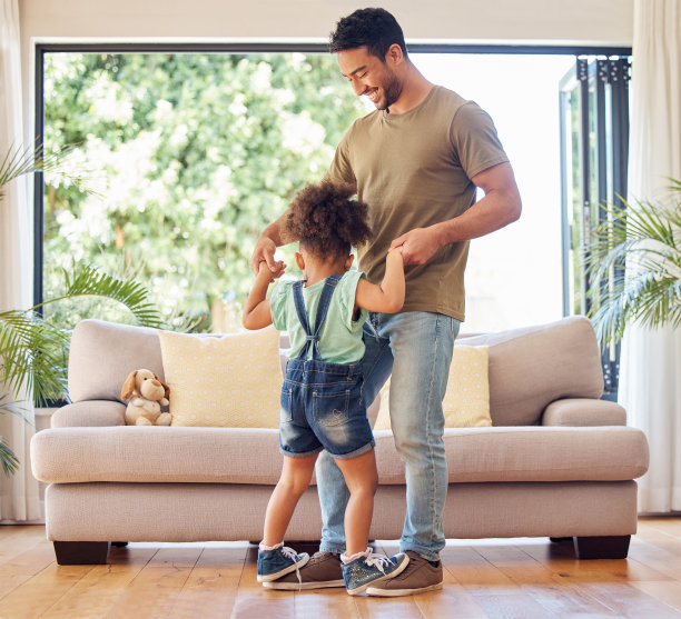 一个英俊的年轻人在家里的客厅里和他可爱的小女儿玩耍的全长镜头图片下载