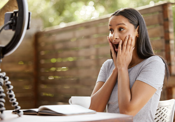一个迷人的年轻女子独自坐在外面，看起来很震惊，她正在用手机上传视频日志图片下载