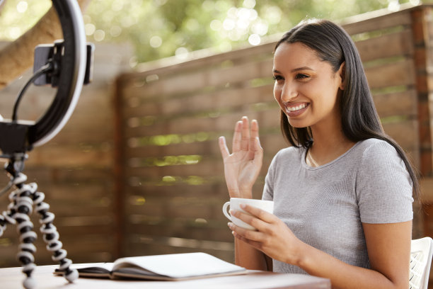 一个迷人的年轻女子独自坐在外面，用她的手机拍视频日志图片下载