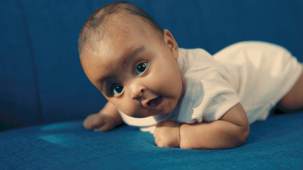 黑孩子躺在蓝色的沙发上图片下载