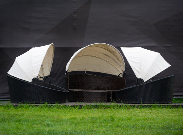 户外草坪上的阳光床，沙滩上的藤椅躺椅，庭院里的圆形柳条床。在后院的家具。图片下载