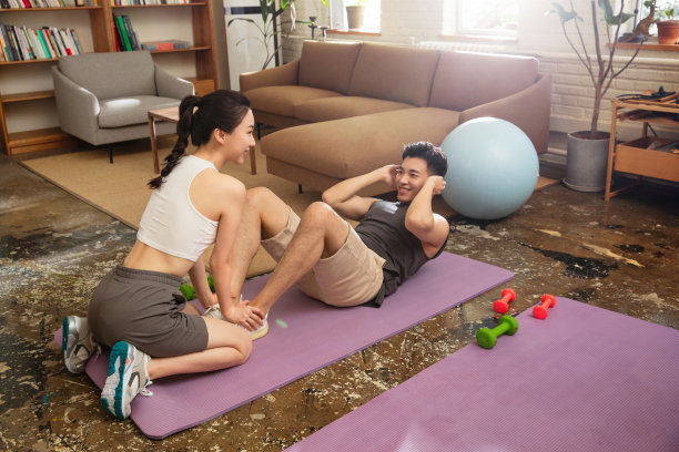 年轻夫妇在家里做仰卧起坐图片下载