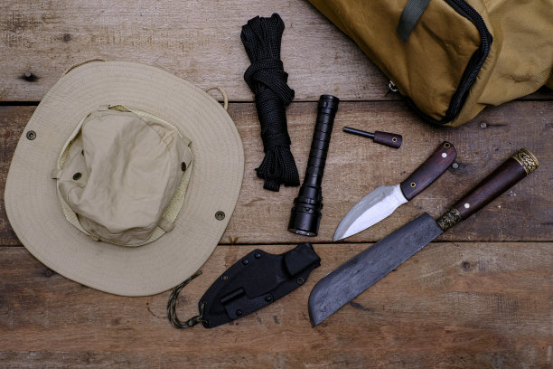 一把带求生装备的刀，放在旧木地板上图片下载