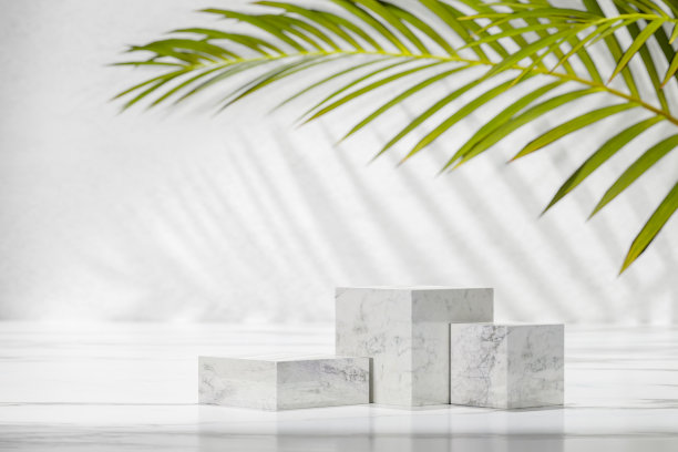 化妆品、护肤化妆品、面霜的背景资料。棕榈叶上三个不同大小的大理石立方体。简单的平台作为产品展示。图片下载