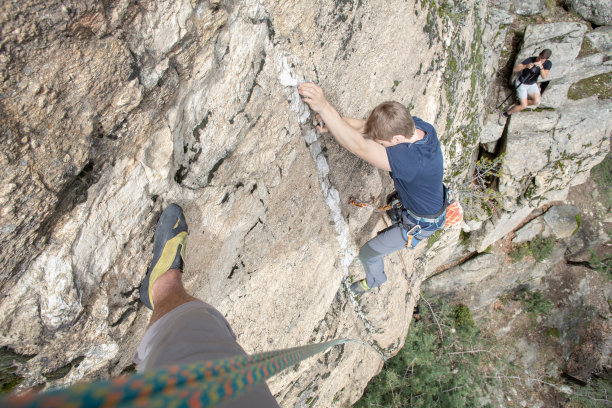 年轻人攀爬垂直岩壁的高角度视图图片下载