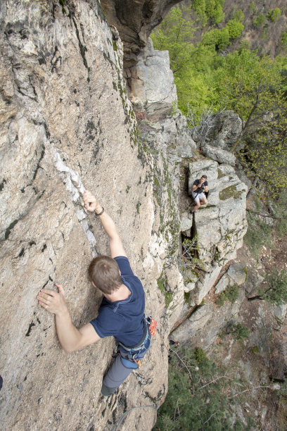 年轻人攀爬垂直岩壁的高角度视图图片下载