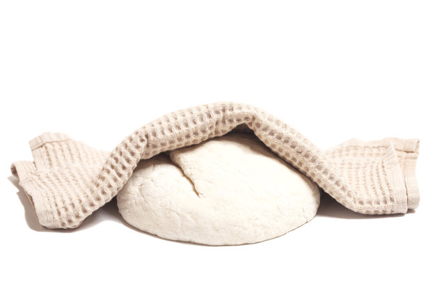 用毛巾覆盖的生酵母面团。概念家庭烘焙或面团制作。孤立在白色背景中图片下载