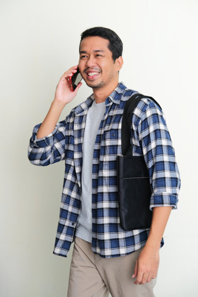 亚洲成年男子散步放松，接听电话，表现出快乐的表情图片下载