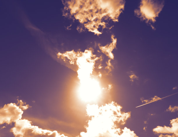 紫色的天空有云和太阳，一架客机飞越天空在云的上面。图片下载