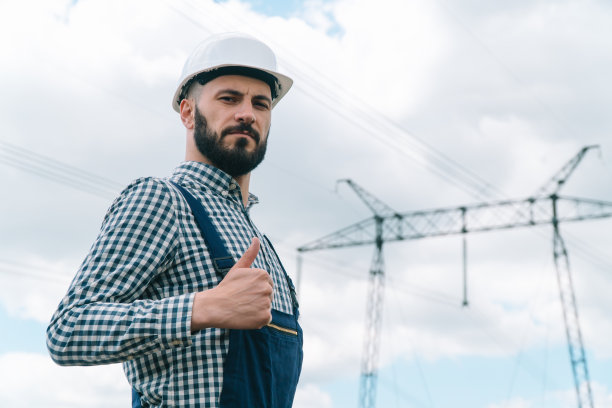 输电线路附近的工程师肖像。能源效率概念。输电塔图片下载