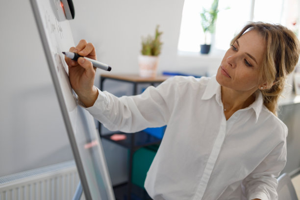 穿着白衬衫的漂亮女教师在白色磁性白板上写笔记图片下载