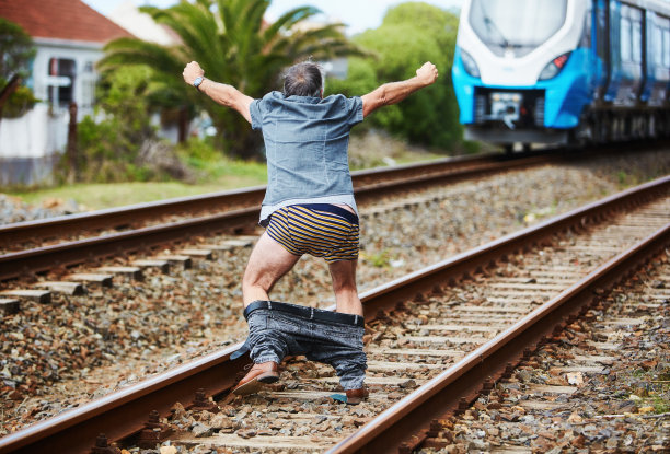 一名愤怒的男子没赶上火车，因为他的裤子掉了，他对正在后退的汽车发火图片下载