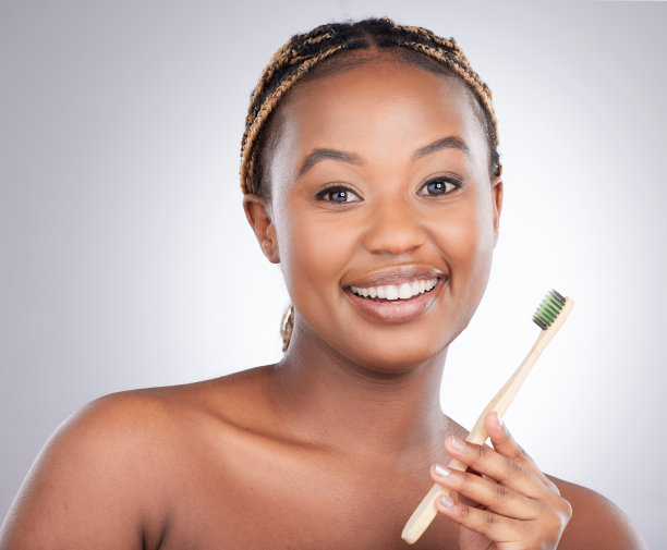 年轻女子在灰色背景前刷牙的影棚照图片下载